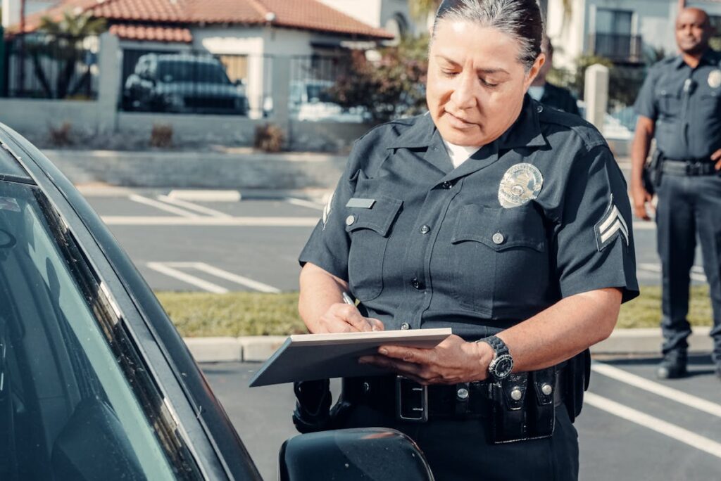 A Police Officer Standing Beside a Car while Holding a Clipboard